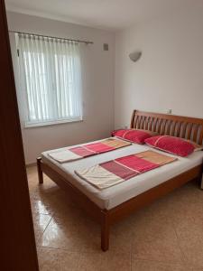 a bedroom with a bed with red pillows and a window at Villa Mane in Donji Štoj