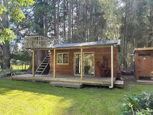 a tiny house with a deck in a yard at Secluded Redwood Cabin in Ashley Clinton