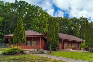 a wooden house with trees in front of it at Lac Sub Soare in Vărbila
