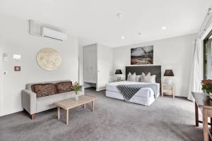 a white bedroom with a bed and a couch at Lime Tree Lodge in Wanaka