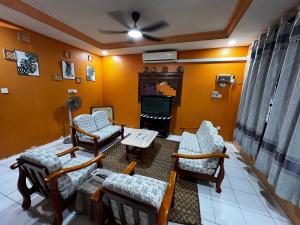 a living room with a couch and chairs and a tv at Aznah’s Stay in Kuching