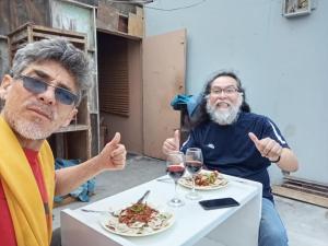 two men sitting at a table with a plate of food at Hospedaje Casa Viru in Lima