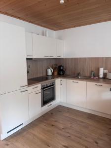 a kitchen with white cabinets and a wooden ceiling at Altefähr Haus 42 in Altefähr +2 photos