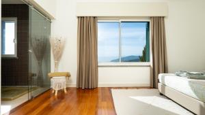 a bathroom with a large window and a tub at DuskLine Villa by LovelyStay in Arco da Calheta +42 photos