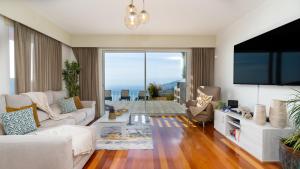 a living room with a couch and a tv at DuskLine Villa by LovelyStay in Arco da Calheta