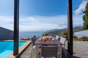 a dining table with a view of the ocean at DuskLine Villa by LovelyStay in Arco da Calheta