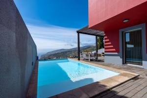 a swimming pool on the side of a house at DuskLine Villa by LovelyStay in Arco da Calheta