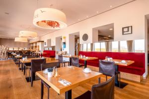 a restaurant with wooden tables and chairs and a red couch at Michels Strandhotel Germania in Norderney