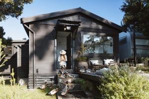 a woman is standing outside of a tiny house at Bushy Summers - A Nurturing Bayside Shack in Strahan