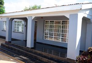 a small white house with a door and stairs at The Residence in Lilongwe