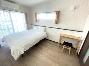 a small bedroom with a bed and a table at コンドミニオ久貝 in Miyako-jima +2 photos