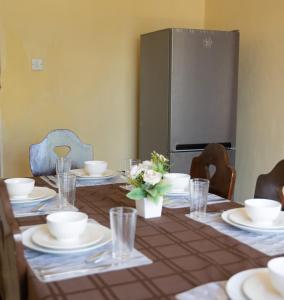 a dining room table with plates and glasses and a refrigerator at The Residence in Lilongwe