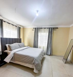 a bedroom with a large bed and two windows at The Residence in Lilongwe