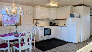 a kitchen with a table and a white refrigerator at Stor älg in Dalskog