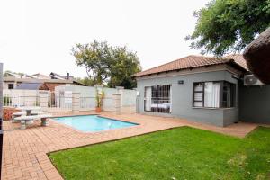a backyard with a swimming pool and a house at Andela Guesthouse in Bloemfontein