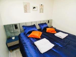 a blue bed with two orange pillows on it at L Oasis Cosy Sauna Privé et Jardin in Bouguenais