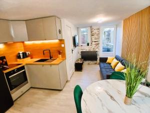 a kitchen and a living room with a couch at L Oasis Cosy Sauna Privé et Jardin in Bouguenais