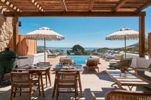 a patio with tables and umbrellas and a pool at The Alexander Estate in Noordhoek