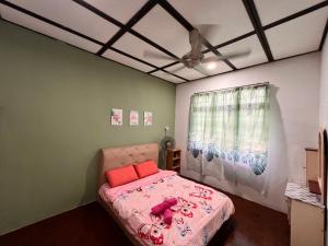 a bedroom with a bed with pink sheets and a window at Aznah’s Stay in Kuching