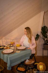 a woman standing in front of a table with food at Les Dômes de Draëck in Zutkerque