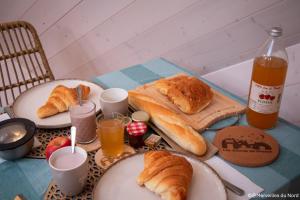 a table topped with plates of croissants and orange juice at Les Dômes de Draëck in Zutkerque +38 photos
