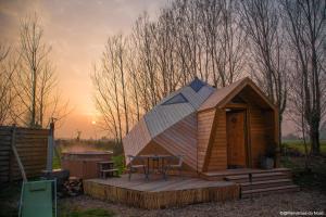 a wooden cabin with a table and chairs on a deck at Les Dômes de Draëck in Zutkerque