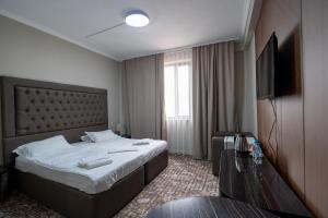 a hotel room with a bed and a television at DeLuxe PLAZA in Almaty