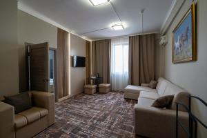 a living room with a couch and chairs in a room at DeLuxe PLAZA in Almaty