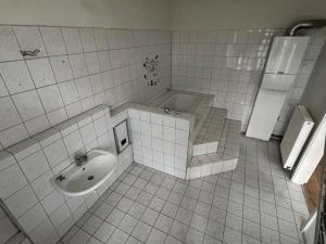 a white tiled bathroom with a sink and a tub at Platin Appartement in Wuppertal