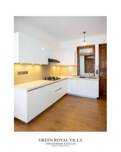 a white kitchen with white cabinets and a wooden floor at Green Royal Villa in Kandy