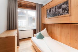 a bedroom with a white couch and a window at adler alpen apartments in Schruns