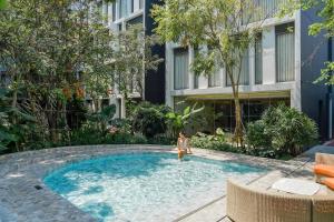 a woman standing in a swimming pool next to a building at NH Hua Hin in Hua Hin