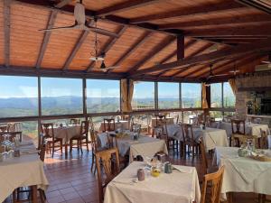 a restaurant with white tables and chairs and windows at Albergo Diffuso Belvedere in Alice Bel Colle