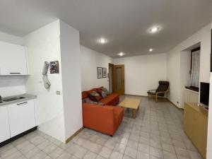 a living room with an orange couch and a kitchen at Appartamento Vadaione Est in Giustino