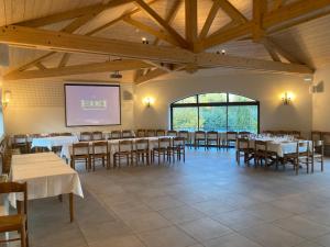 a dining room with tables and chairs and a projection screen at Aux Vieux Arceaux in Mercuer