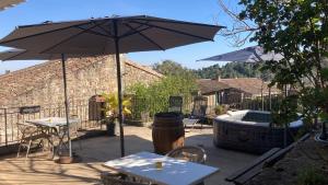 a patio with a table and an umbrella and a tub at Aux Vieux Arceaux in Mercuer