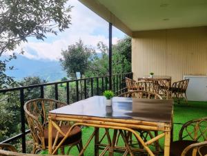 a table and chairs on a balcony with a view at 7 Hills Resort Kanatal in Kanatal