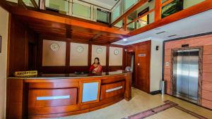 a woman standing at a bar in a building at Hotel White City in North Paravur