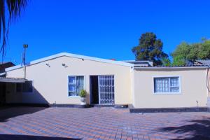 a white house with a brick driveway at Inspan Home & Lodge in Bellville South