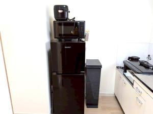 a black refrigerator with a microwave on top of it at LemonRooms in Aomori +19 photos