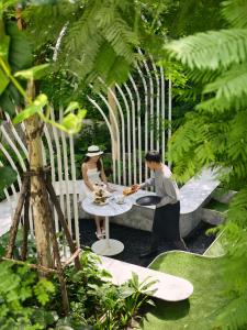 a man and woman sitting at a table in a garden at NH Hua Hin in Hua Hin