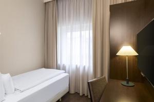 a hotel room with a bed and a window at NH Düsseldorf Königsallee in Düsseldorf