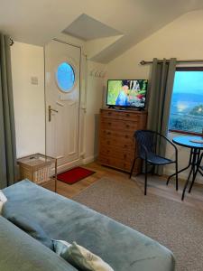 a bedroom with a bed and a tv and a table at The Orchard Cabin in Cardington