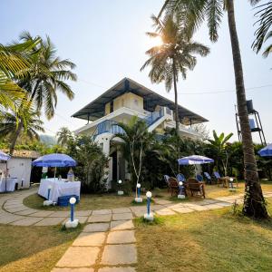 a house with tables and umbrellas in front of it at EKAM in Agonda