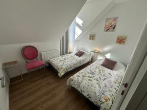 a bedroom with two beds and a red chair at Le Valory in Granville