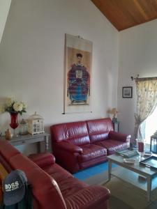a living room with a red leather couch and a table at Villa Thierry in Leiria