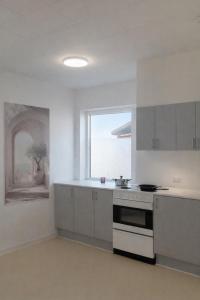 a kitchen with white cabinets and a large window at PAK Central apartment Odense C in Odense