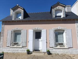 a pink house with two windows and a white door at Petite Maison a deux pas du centre in Le Faou