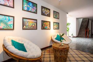 a living room with two white chairs and paintings on the wall at Mera Residence in Siem Reap +50 photos
