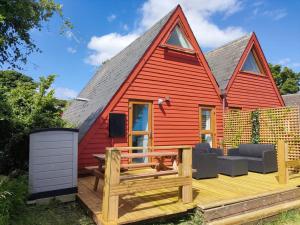 a red house with a deck and a tv at Chalet Thirtyone in Deal